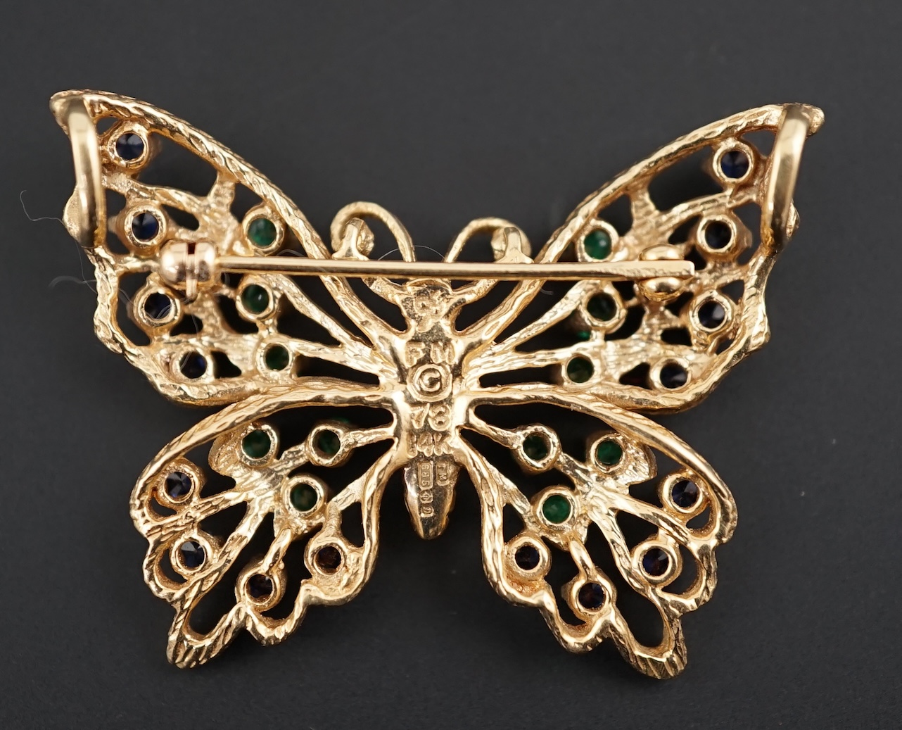A modern pierced 14ct gold, emerald and sapphire cluster set butterfly brooch